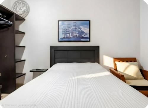 a bedroom with a white bed and a tv on the wall at El descanso del guerrero in Barra Vieja