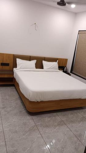 a bedroom with a large bed with white sheets and pillows at Hotel Dwarkesh in Dwarka
