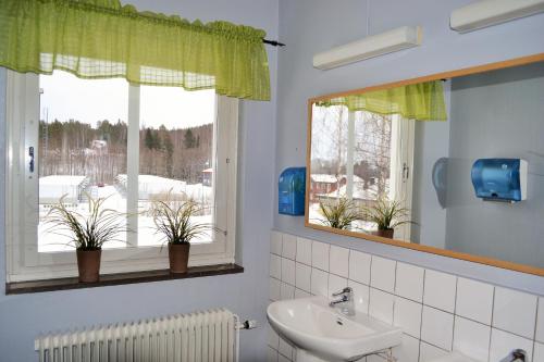 een badkamer met een wastafel en een raam met potplanten bij Södra Bergets Vandrarhem in Sundsvall