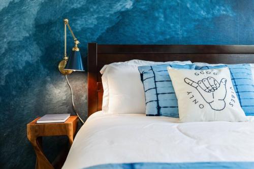 a bed with a pillow with a hand painted on it at Bella Blu in Avila Beach