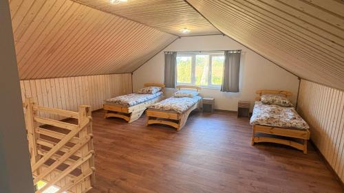 an attic room with three beds and a window at Domki letniskowe Hamer in Łeba