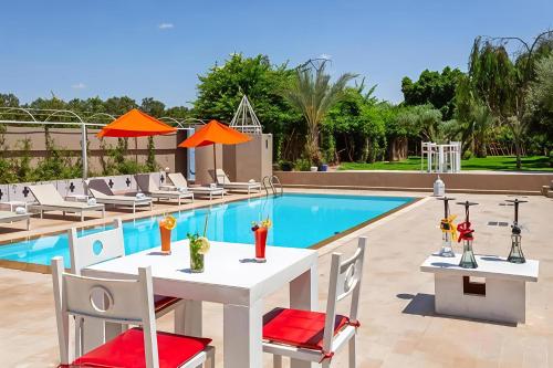 a table and chairs next to a swimming pool at Palais Jena Hotel & Spa in Marrakesh