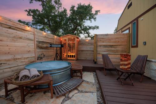 a hot tub on a deck with two chairs at Romantic Tiny Luxury Retreat w heated pool, sauna n outdoor shower in Wimberley 10 acres in Wimberley