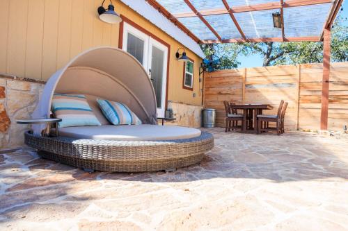 a wicker bed on a patio with a table at Romantic Tiny Luxury Retreat w heated pool, sauna n outdoor shower in Wimberley 10 acres in Wimberley