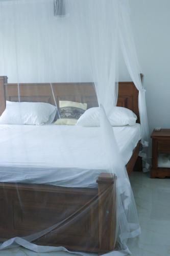 a bedroom with a bed with white sheets and pillows at Nela House in Galle