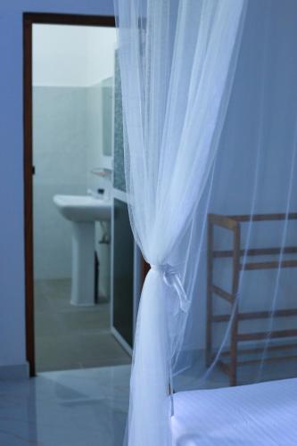a bedroom with a bed and a bathroom with a mirror at Nela House in Galle