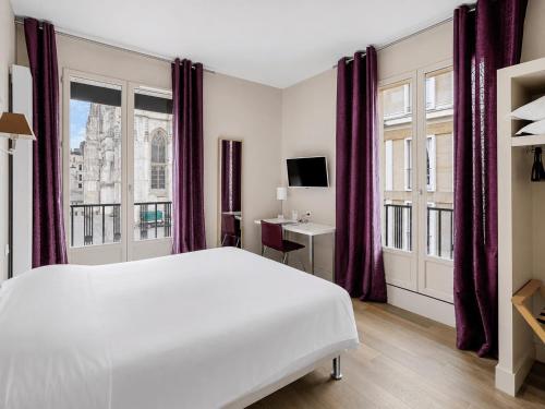 a bedroom with a large white bed and windows at Hôtel Cardinal in Rouen