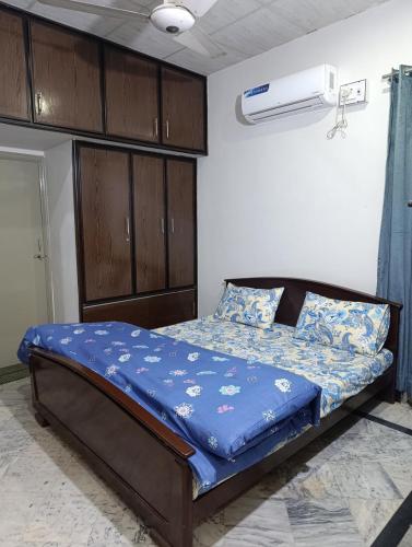 a bedroom with a bed with a blue comforter at Alnoor Lodgings in Rabwāh