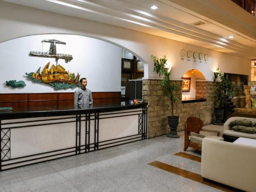 a man standing at a counter in a lobby at Grand Kalimas Hotel in Surabaya