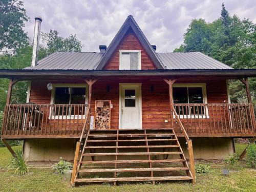 a log cabin with a porch and a staircase leading to it at Repère de la Rivière - Bord de l'eau- Activités nautiques in Saint-Alexis-des-Monts