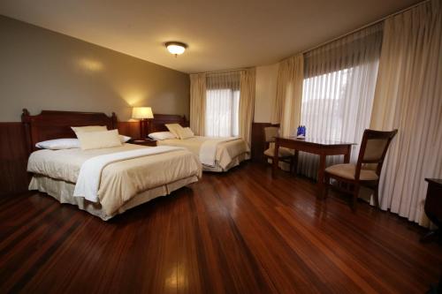 a hotel room with two beds and a desk at Hotel Spa CASA REAL in Riobamba