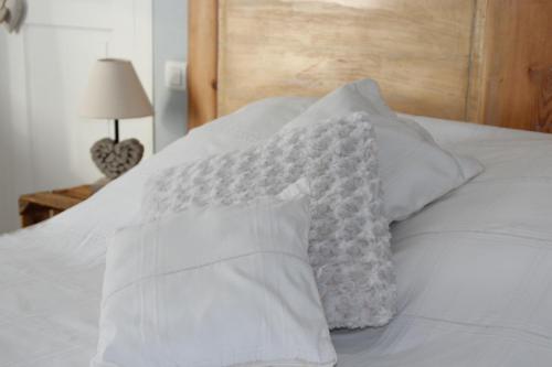 a white bed with white pillows on it at Au repos du roi in Maisoncelle