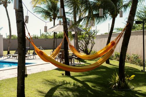 a hammock hanging between two palm trees next to a pool at Pousada Tropical Ilhas in Aquiraz