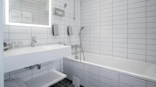 a white bathroom with a tub and a sink at Thon Hotel Slottsparken in Oslo