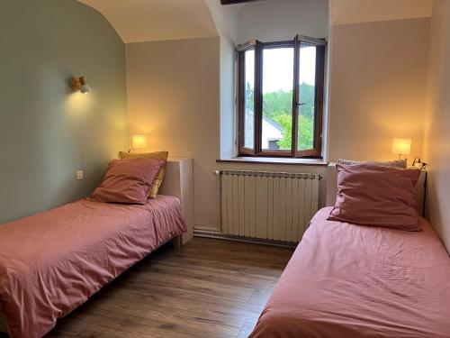 two beds in a room with a window at Maison d'hôtes- éco tourisme in Moux-en-Morvan