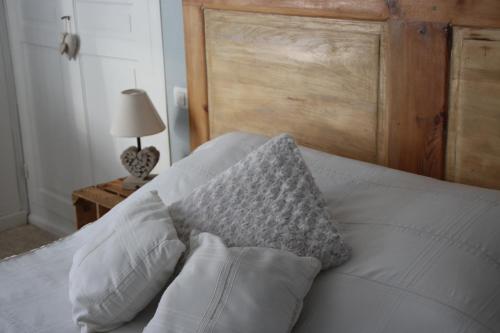 ein Bett mit weißen Kissen und einem Kopfteil aus Holz in der Unterkunft Au repos du roi in Maisoncelle