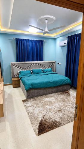 a bedroom with a bed with blue walls and blue curtains at the urban escape in Kwabenyan