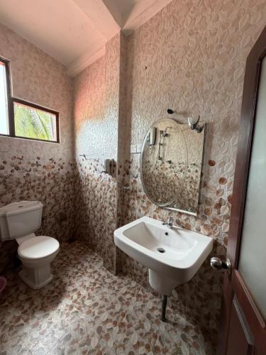 a bathroom with a sink and a toilet and a mirror at Nuwanma in Halpatota