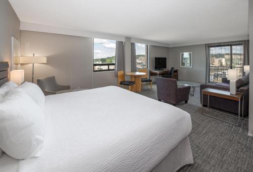 a hotel room with a large bed and a living room at Coast Prince George Hotel in Prince George