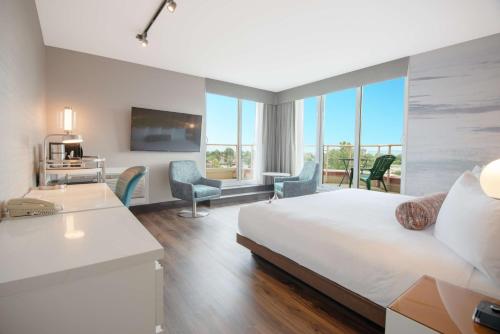 a hotel room with a bed and a desk and chairs at Coast Victoria Hotel & Marina by APA in Victoria