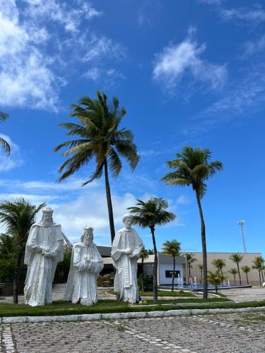 a statue of three people standing next to a palm tree at Pirâmide Palace Hotel in Natal