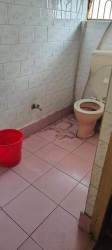 a bathroom with a toilet and a bucket on the floor at Anand Vihar in kolkata