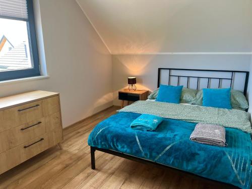 a bedroom with a bed with blue sheets and a window at Domki Weekend in Łeba