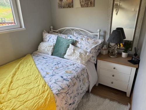 a bedroom with a bed and a night stand with a mirror at Kabin in the woods with Hot Tub in Llandybie