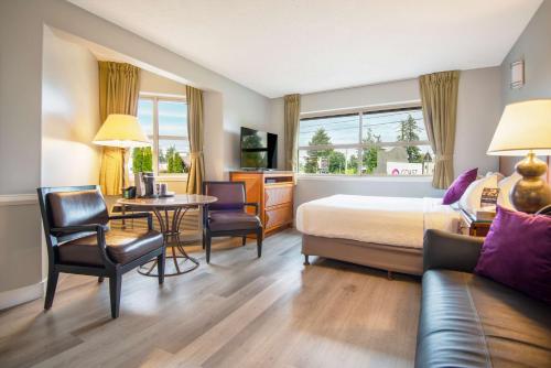 a hotel room with a bed and a table and chairs at Coast Parksville Hotel in Parksville