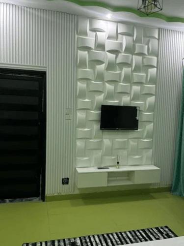 a white wall with a television in a room at Hôtel La Parisienne in Louga