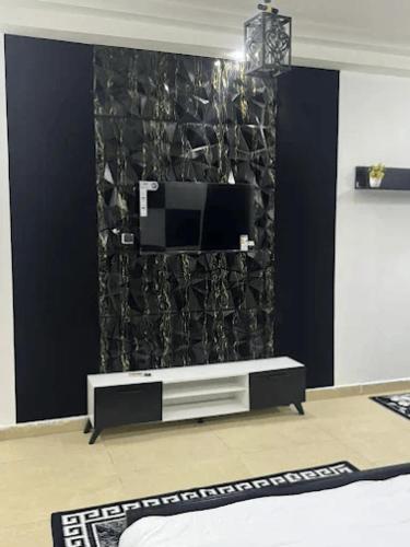 a living room with a tv on a wall at Hôtel La Parisienne in Louga