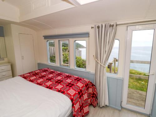 a bedroom with a bed and a window with the ocean at Clifftop Carriage in Aberporth