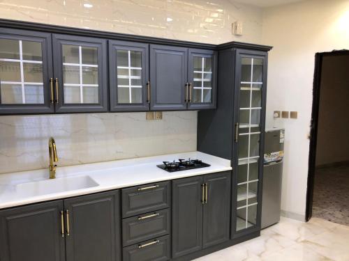 a kitchen with gray cabinets and a sink and a refrigerator at شالية خاص in Khamis Mushayt