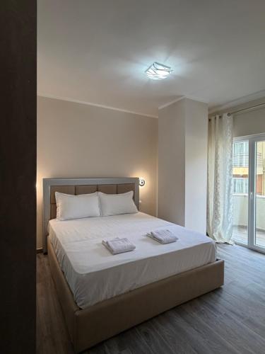 a bedroom with a bed with white sheets and a window at Apartamente Shengjn in Shëngjin