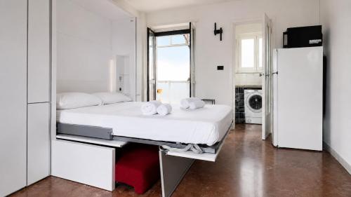 a white bedroom with a bed and a refrigerator at oasi relax Jacuzzi ultimo piano in Turin