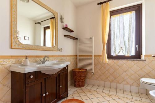 a bathroom with a sink and a mirror and a toilet at Casa Konny in Gonnostramatza