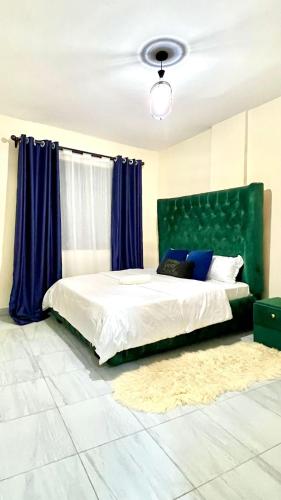 a bedroom with a bed with a green headboard at 2 Bedroom Apartment Kitengela in Kitengela 