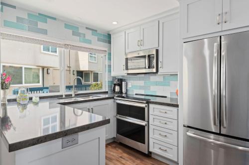 a kitchen with white cabinets and a stainless steel refrigerator at Seaside Retreat at Solimar Sands in Carpinteria