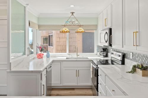 a white kitchen with white cabinets and a window at Sandbox at Solimar Sands in Carpinteria