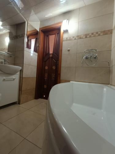 a bathroom with a tub and a sink and a door at Pokoje gościnne u Krupy in Murzasichle