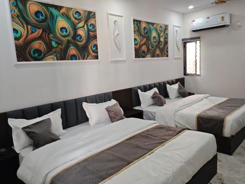 two beds in a room with paintings on the wall at Hotel Shree Kesari Nandan in Dwarka