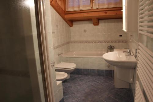 a bathroom with a toilet and a sink and a tub at Casa Monego in Fusine