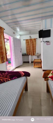 a bedroom with two beds and a television in it at S K S HOME STAYs in Vālpārai
