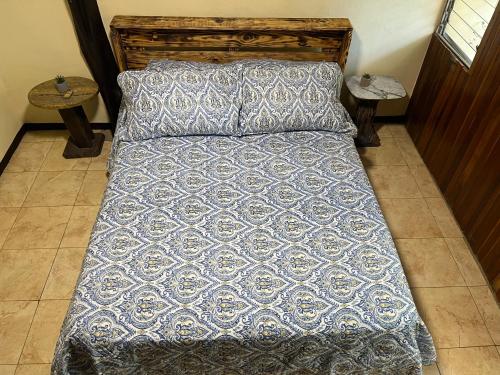 a bed with a blue comforter and two tables at Rincón del río B&B in Ángeles