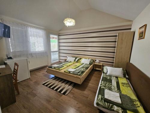 a bedroom with two beds and a window at Party Vendégház in Hajdúszoboszló