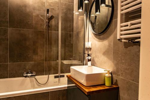 a bathroom with a sink and a shower and a mirror at Apartament 24 in Mysłowice