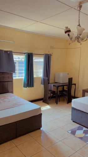 a bedroom with a bed and a table and chairs at Quantico Guest house villa in Ndola