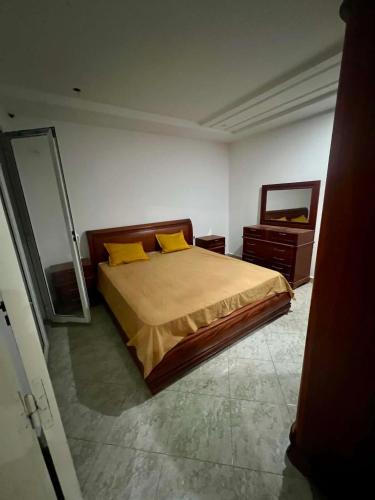 a bedroom with a bed with yellow pillows and a mirror at Dar Meriem in Korba