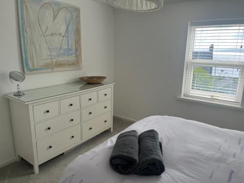 a bedroom with a white bed with a dresser at Coastal Charm Seaside House in Moelfre