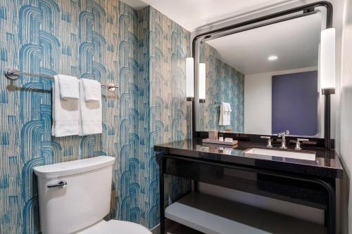 a bathroom with a toilet and a sink and a mirror at Hotel Mockingbird, Dallas, a Tribute Portfolio Hotel in Dallas